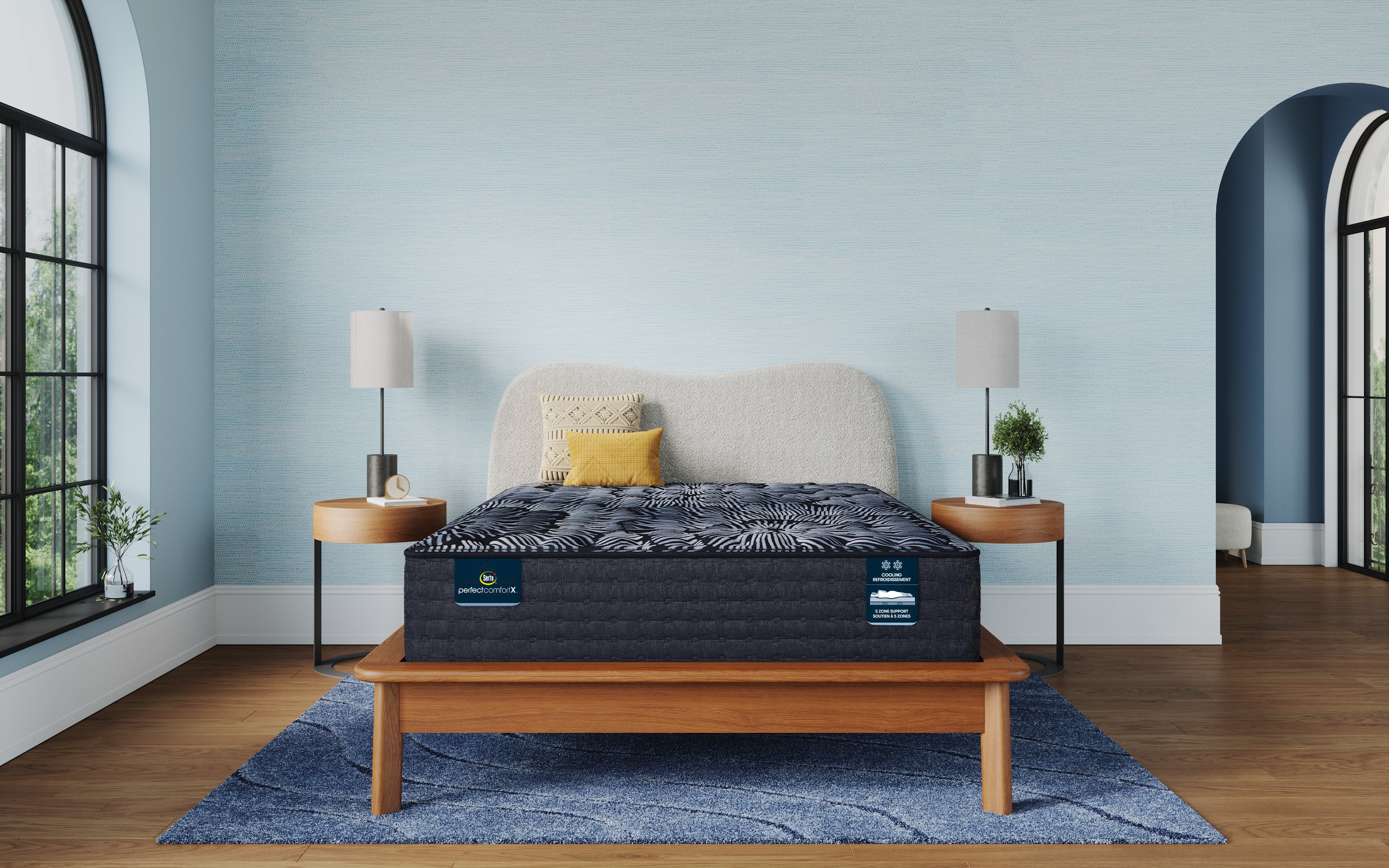 Mattress on a wooden bed frame in a room with light blue walls and large windows.