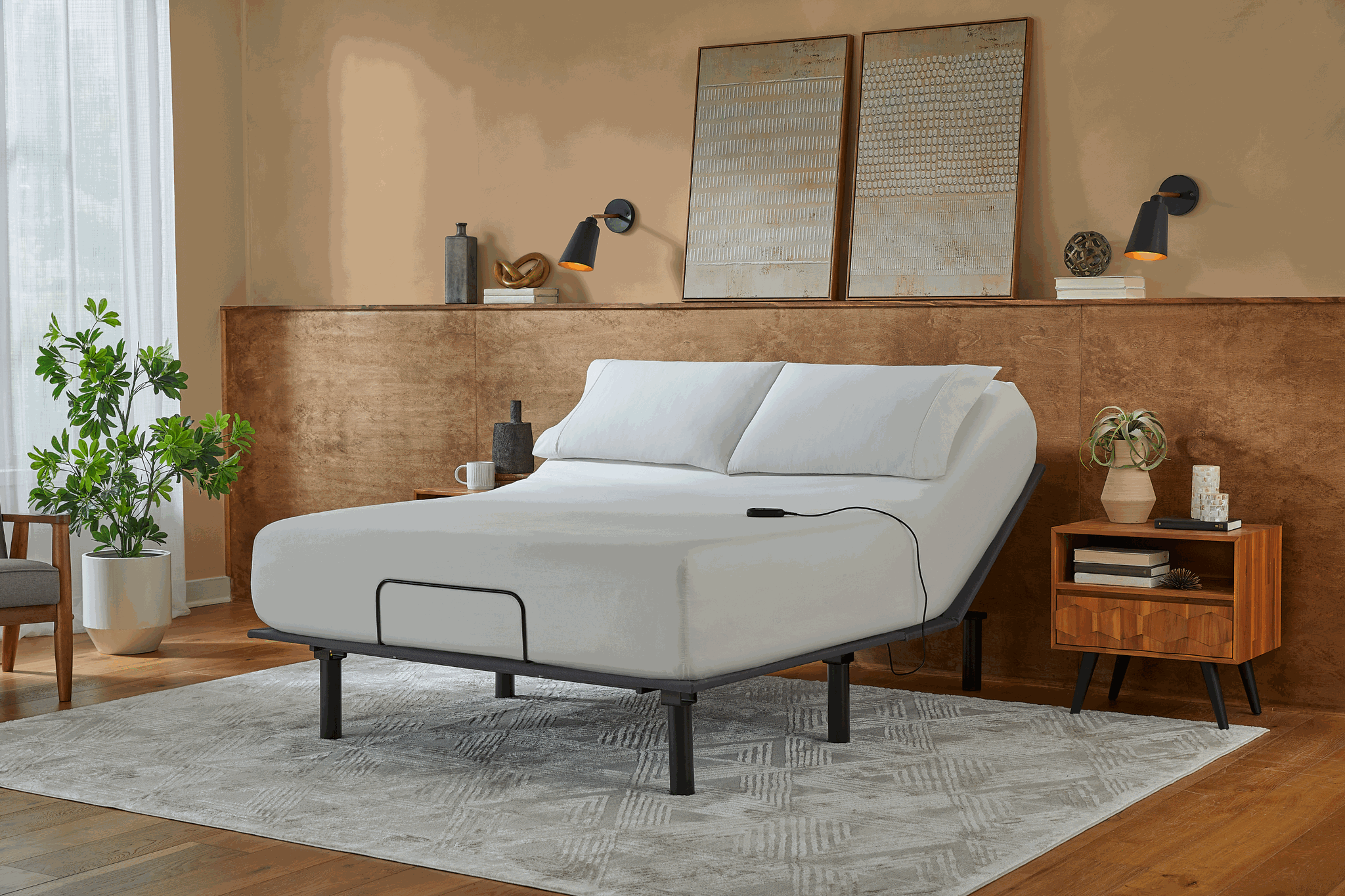 Gray adjustable bed in a bedroom setting with wooden furniture and decor.