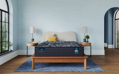 Mattress on a wooden bed frame in a room with light blue walls and large windows.