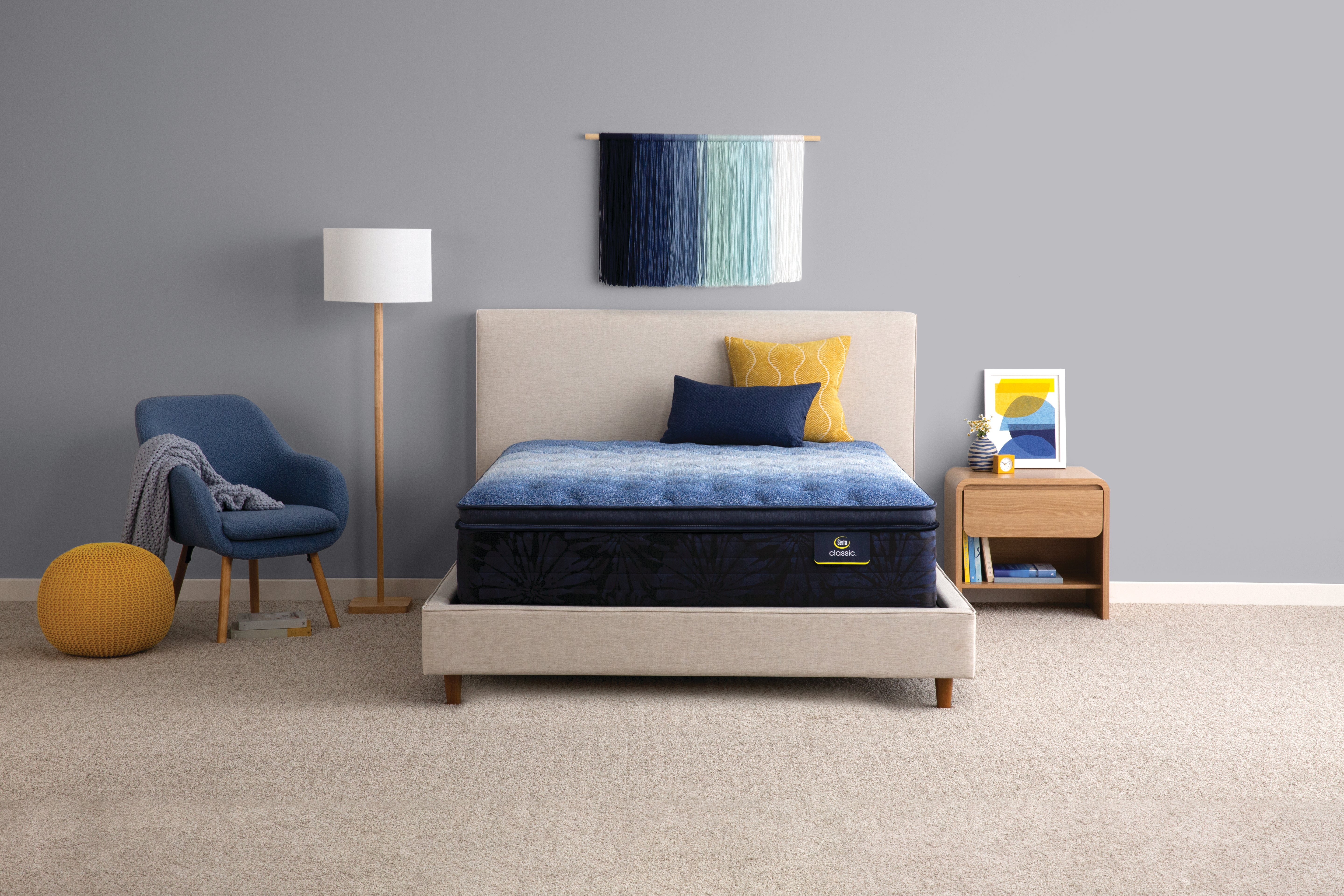Bedroom with a mattress on a bed, lamp, chair, and small table.