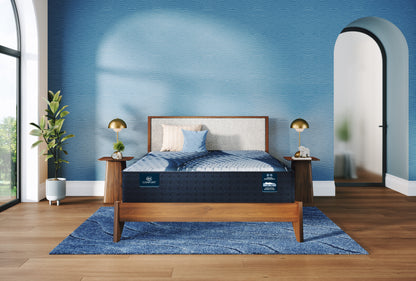 Bed with a blue mattress in a room with a blue wall and wooden floor.